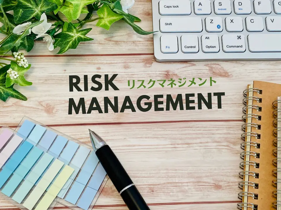 RISK MANAGEMENTの文字とキーボード、ペン、ノートの画像
