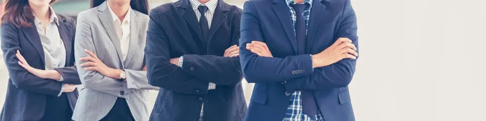 スーツ姿で腕組みをして立つ4人の男女