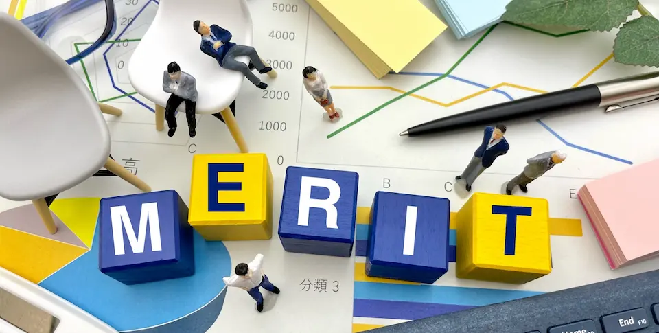 積み木にMERITの文字と5人のビジネスパーソン。背景・折れ線グラフ