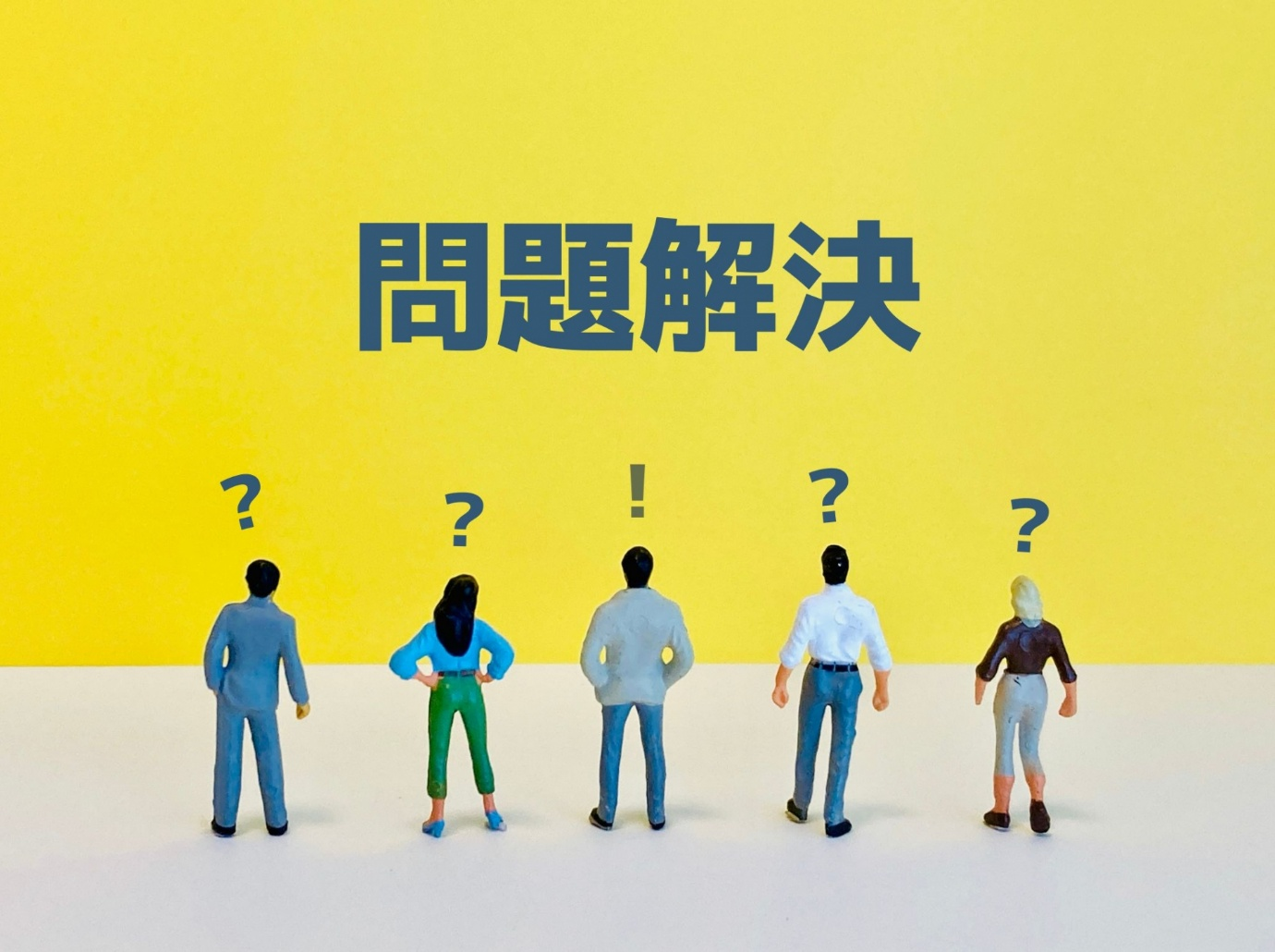 問題解決の文字と、それを見上げる5人のビジネスパーソン