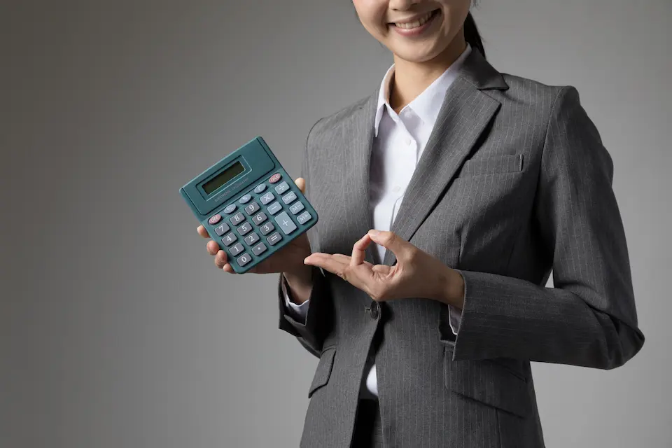 電卓を手にした女性が指でOKをしている画像