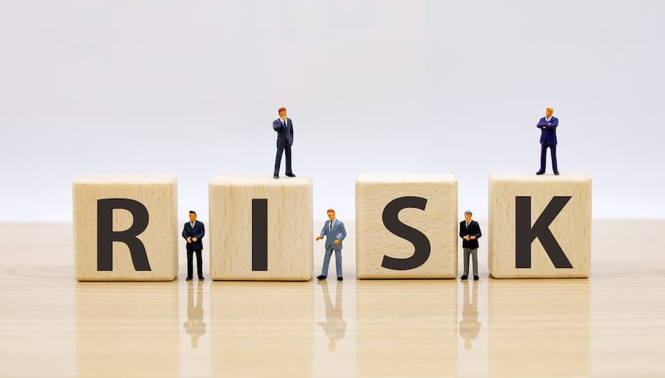 RISKという文字の積み木と5人のビジネスマン