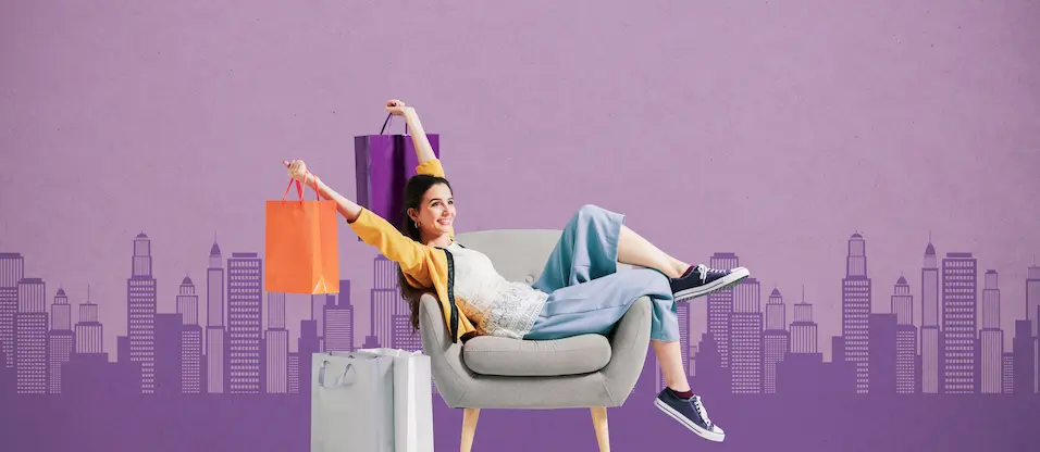 女性がショッピングバックを両手にして椅子に座り万歳のポーズをしている