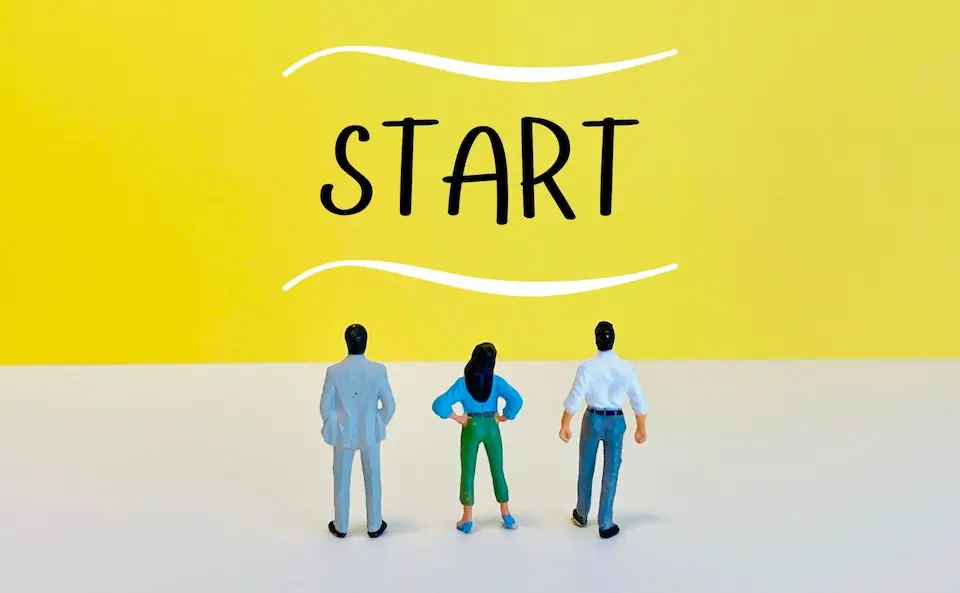 STARTという文字を眺める3人のビジネスパーソン