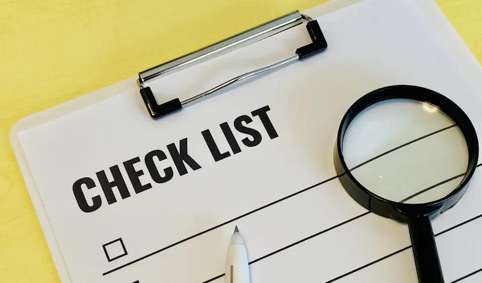 バインダーにはさんだチェックリストと虫眼鏡とペン先