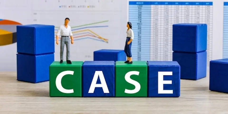 CASEと書かれた積み木、男女のビジネスパーソン、背景にグラフ