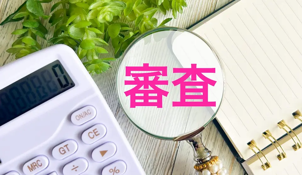 審査の文字とノート、電卓